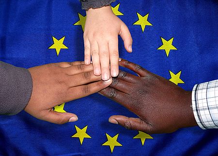 foto mani Migranti con sfondo bandiera europea